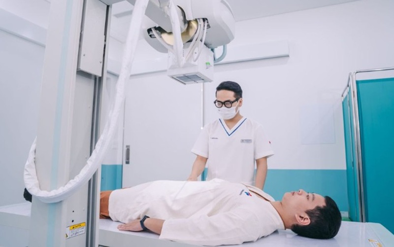 Nhân viên y tế hỗ trợ người bệnh thay đổi tư thế nằm trong quá trình thực hiện chụp X-quang dạ dày
